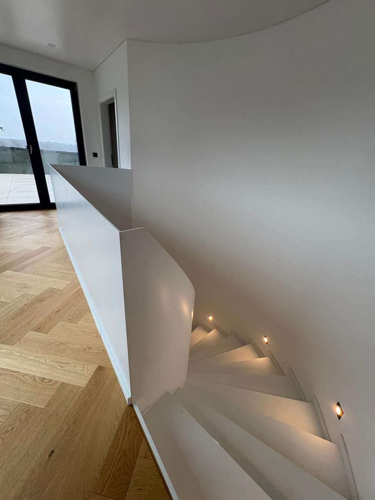 Geschlossene weiße Brüstung an einer gewendelten Treppe – Referenz von AN Metallbau