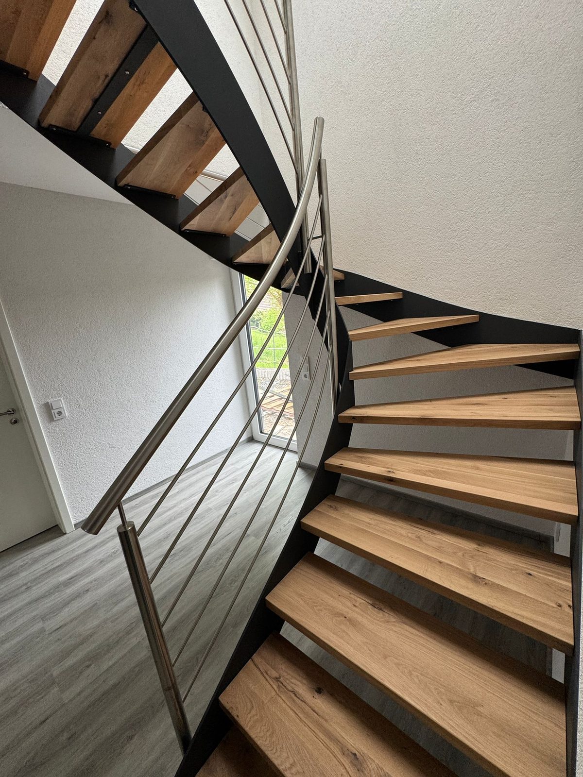 Gewendelte Innentreppe mit Holzstufen und Stahlwange – AN Metallbau GmbH